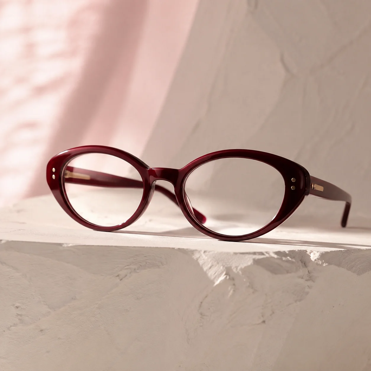 Burgundy oval optical frame on a sculpted plinth